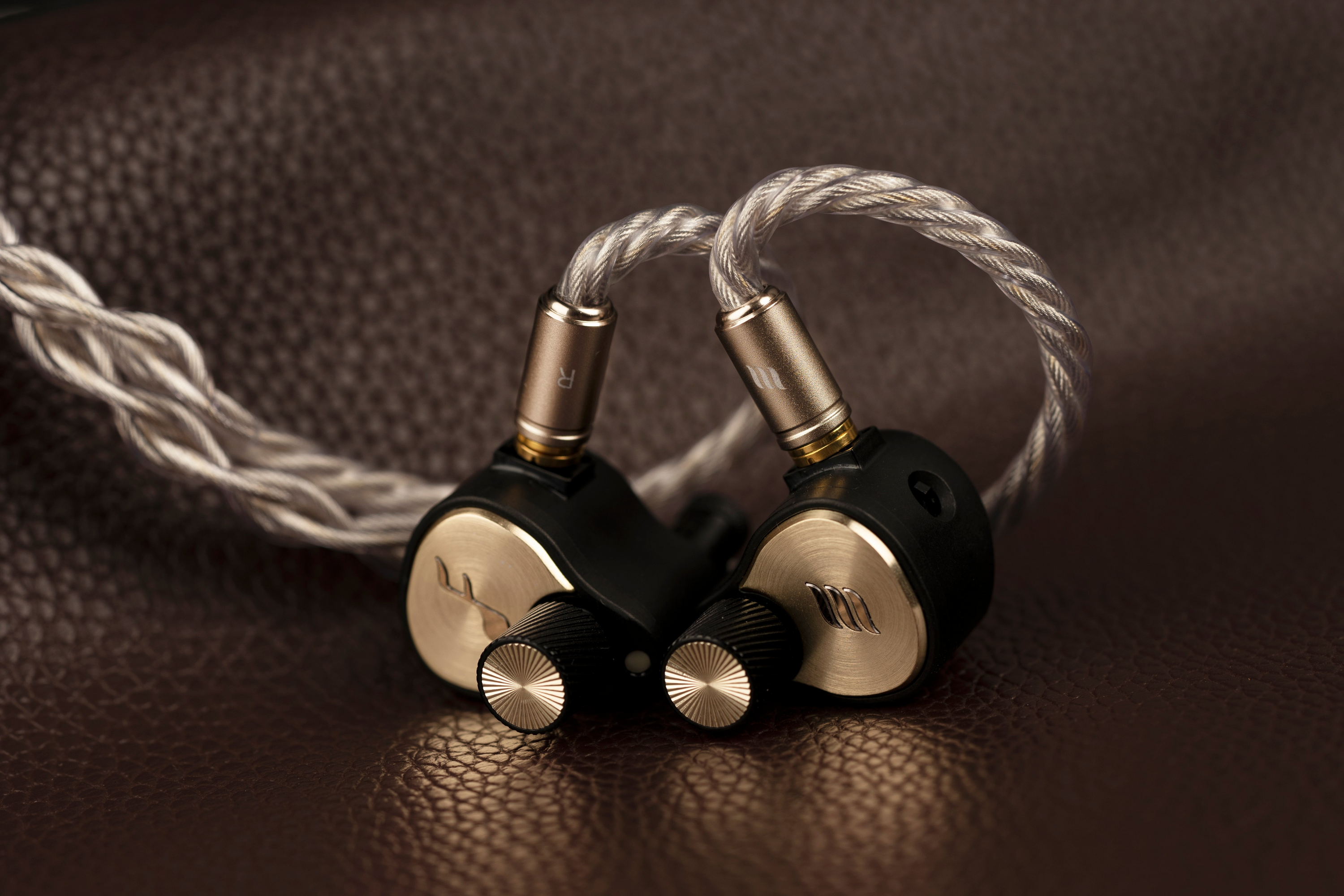 Pair of high-end audio earbuds on a brown textured background