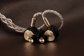 Pair of high-end audio IEMs on a textured brown surface